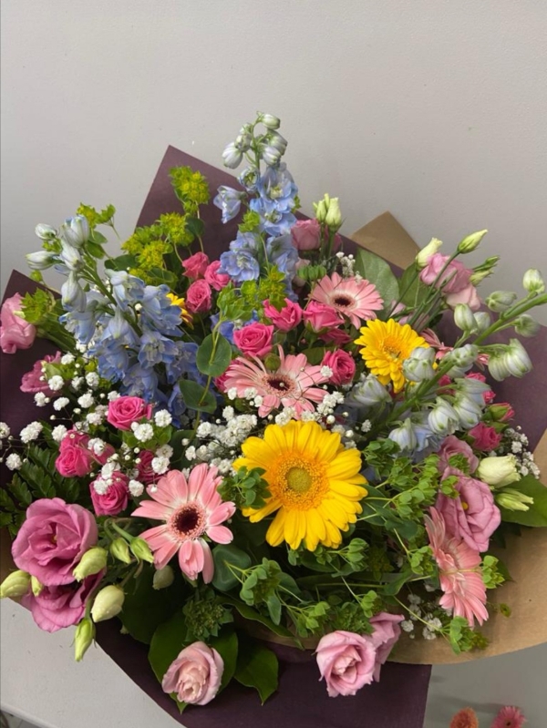 Mixed garden style bouquet to include blue delphiniums, cerise spray roses, pink Lisanthius, gypsophilium, daisies