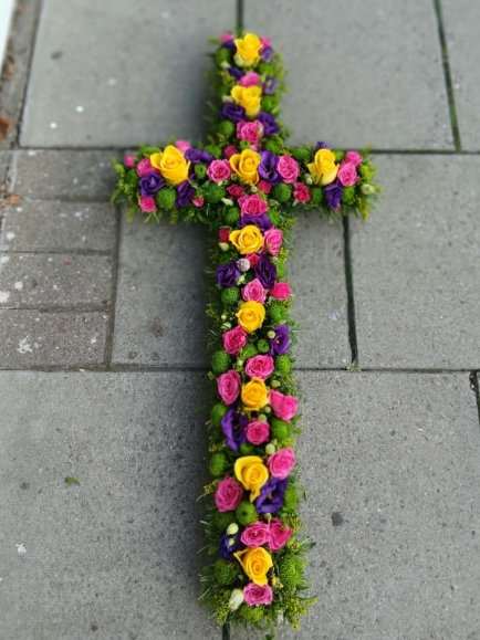 Mixed flowers vibrant cross with cerise roses, yellow daisy, yellow spray roses, purple Lisanthius, lilac fillers. Made by florist in Croydon, Surrey, UK