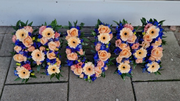 Mix of peach roses and gerberas with blue delphinium and thistle with greenery. By Croydon Blooms Funeral Florist in Croydon, UK