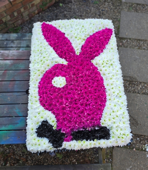 funeral flowers Playboy pink bunny on white designer board.