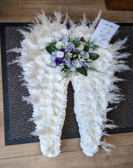 White based wings with addition with white feathers and pampas grass. Spray in the middle can be changed. By Croydon Blooms Florist