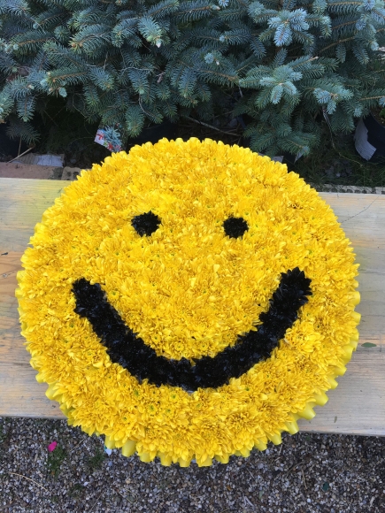 yellow sprayed posy pad with a smiling face. Any emoji face can be done. By Croydon Blooms Florist