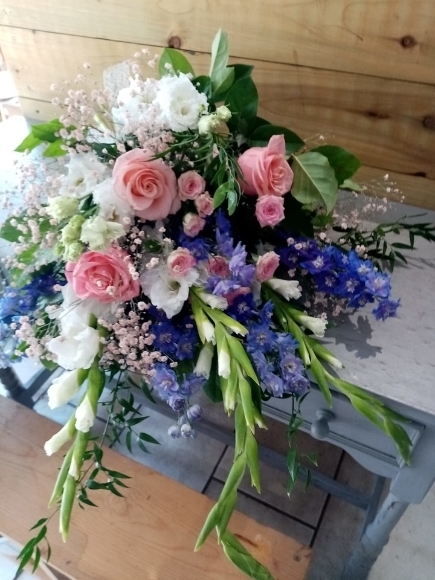 beautiful composition of white long flowers with blue delphiniums and soft pink roses by funeral florist from Croydon, UK