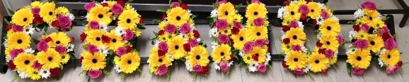 Mixed vibrant letters made of yellow daisies, hot pink roses and white chrysanthemums. By florist in CR