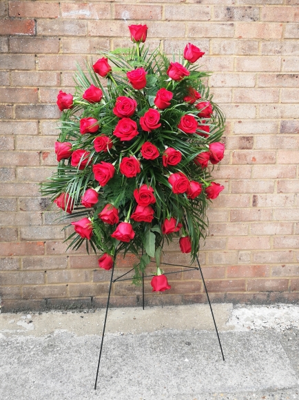 Red roses funeral flowers spray on easel