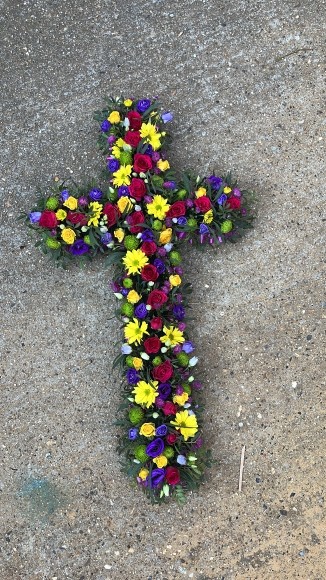 Mixed flowers vibrant cross with cerise roses, yellow daisy, yellow spray roses, purple Lisanthius, lilac fillers. Made by florist in Croydon, Surrey, UK