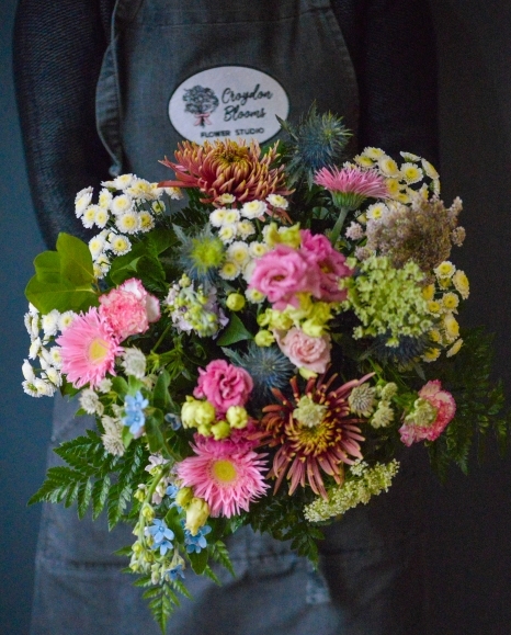 A bouquet of garden flowers in purples, lilacs and pinks made by Croydon Blooms florist.