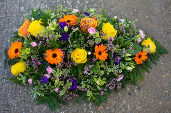 Vibrant teardrop funeral spray with yellow and orange flowers made by florist in Bromley, Kent, UK