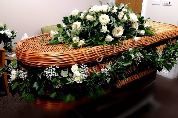 funeral garland and coffin spray set with roses for a wicker coffin arranged by florist in Bromley