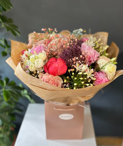 2 types of pink peony, large pink roses, scented sweet alliums, Lisanthius, agapanthus and coloured Gypsophilium tied in luxury compact bouquet. Early summer in full bloom Made by florist in Croydon, Surrey, UK