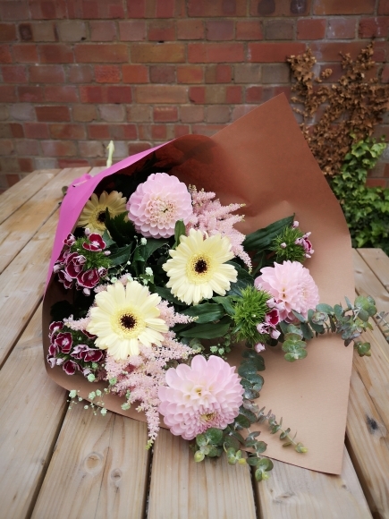 pink flowers with dahlias, astilbe, sweet william, daisies nicely wrapped in eco paper on the wooden table from Croydon blooms flower studio in Croydon, surrey