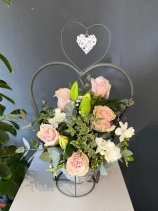 Stunning scented design with roses, freesias and lily arranged in wicker metal heart pot which can be reused as a porch planter. By florist in Croydon, Surrey, UK