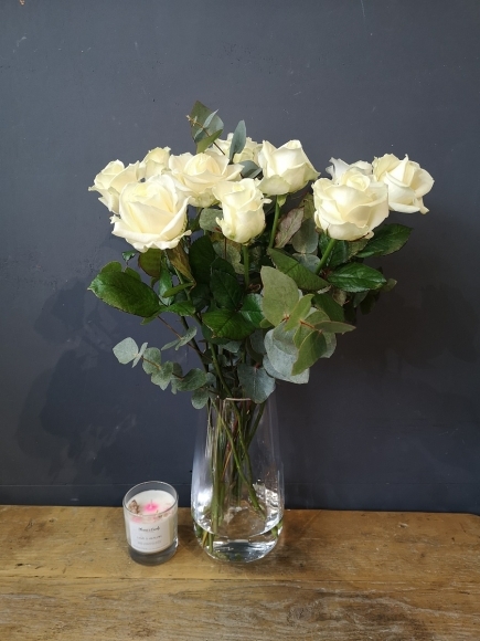 white roses bouquet in tall glass vase with eucalypthus